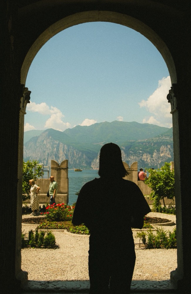 Silhouette in einem Torbogen mit Blick auf Garten und See