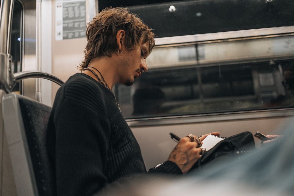 Junger Mann zeichnet in der Metro in ein Skizzenbuch