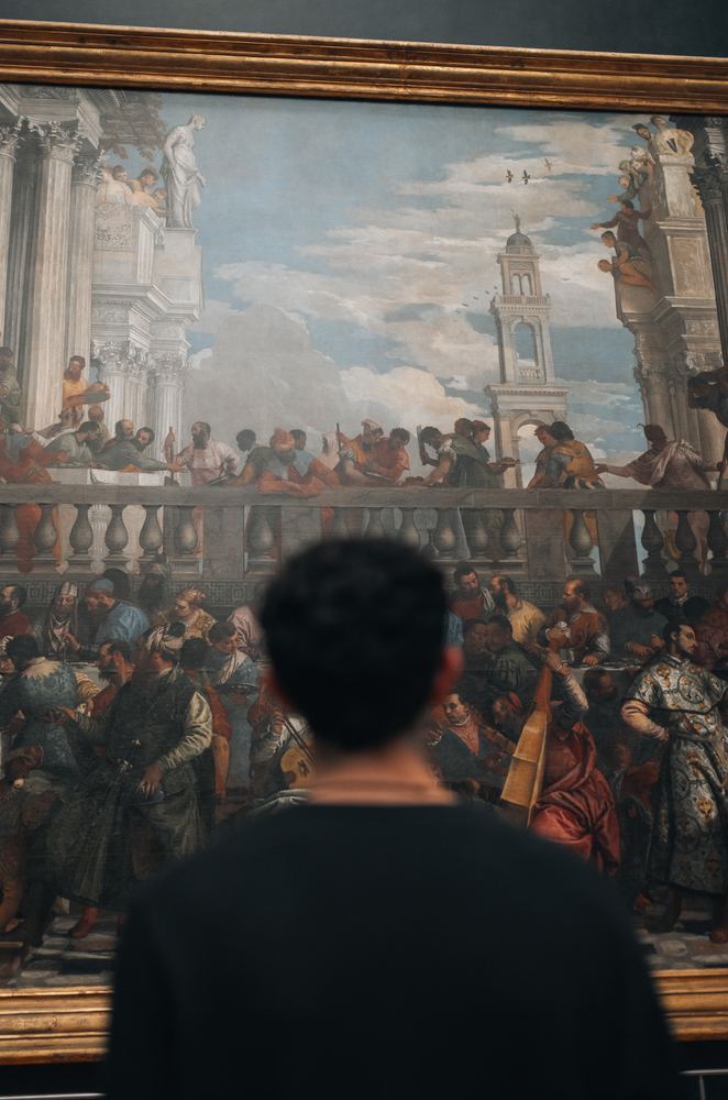 Besucher von hinten vor einem großen Gemälde im Louvre
