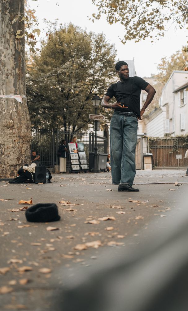 Mann in weiter Jeans steht auf einer Straße mit Herbstlaub