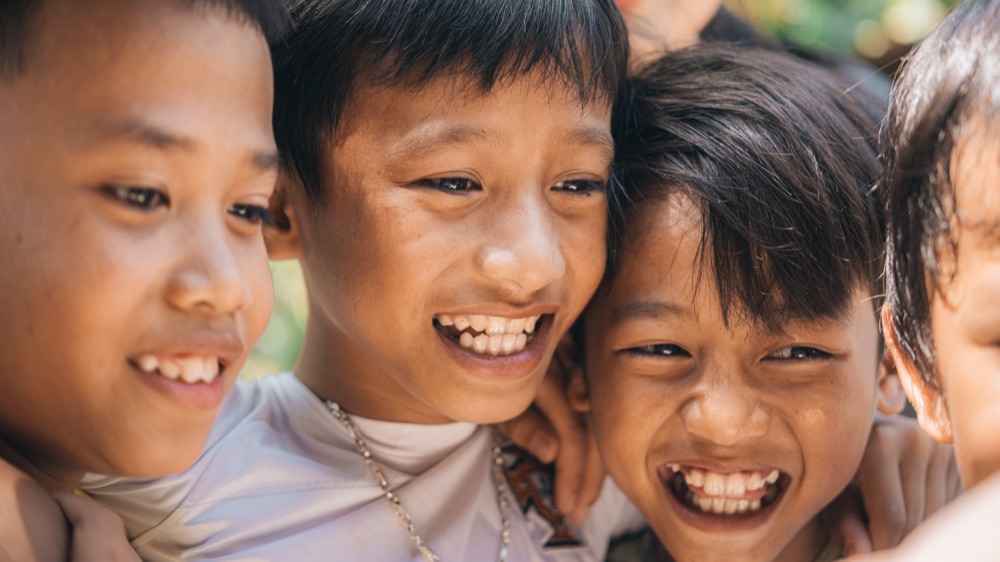 Drei Jungen lachen dicht nebeneinander